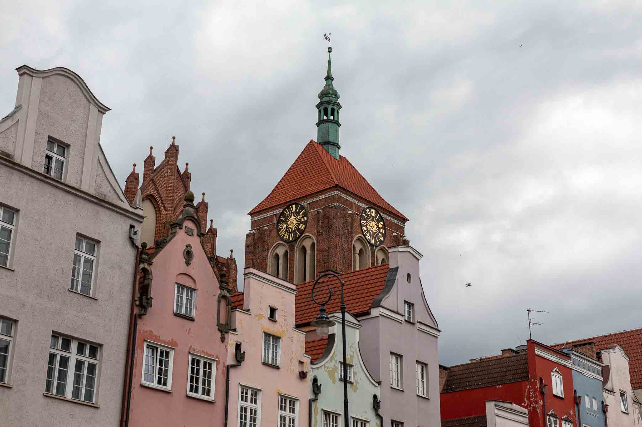 Der Turm der Johanneskirche vor einer bunten Hausgruppe in Danzig